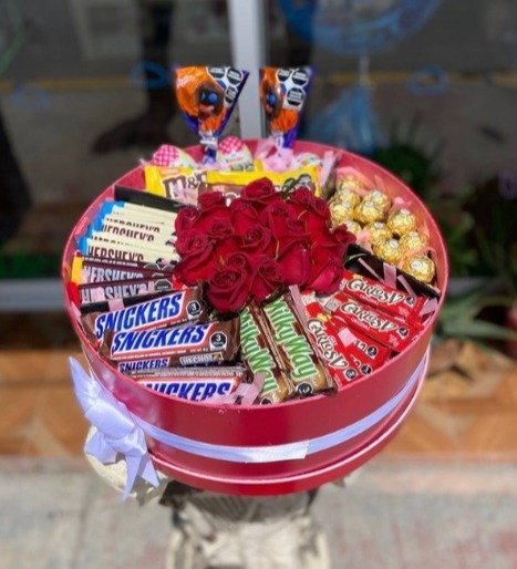 Arreglo con 12 rosas rojas y chocolates variados en cajonera circular