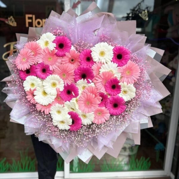 Ramo de 36 gerberas tonos pastel, en forma de corazón y follaje baby rosa